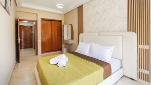 Quarto de hotel com cama, guarda-roupa de madeira, espelho e porta.