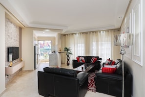 Ein modernes Wohnzimmer mit einer schwarzen Ledersofa, einem Couchtisch und einem an der Wand montierten Fernseher.