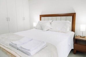 A bedroom with a bed, pillows, a bedside table, a lamp, and a wardrobe. - Newly Renovated 2BR Apartment in Lima (Lince)