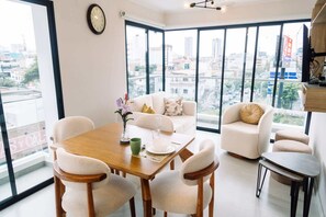 A spacious room with a large window, a dining table, white sofas, and a small round table. - Newly Renovated 2BR Apartment in Lima (Lince)