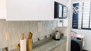 A kitchen with a microwave, coffee maker, and washing machine. - Newly Renovated 2BR Apartment in Lima (Lince)