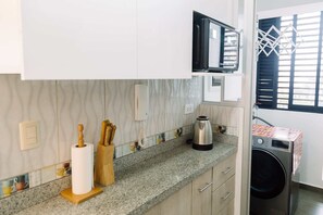 A kitchen with a microwave, coffee maker, and washing machine. - Newly Renovated 2BR Apartment in Lima (Lince)