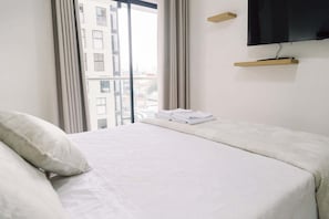 A hotel room with a bed, a TV mounted on the wall, a window with curtains, and a city view. - Newly Renovated 2BR Apartment in Lima (Lince)