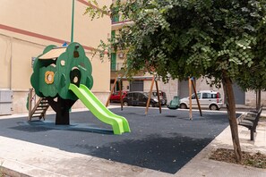 Ein Spielplatz mit Rutsche, Schaukeln und einem Baum.