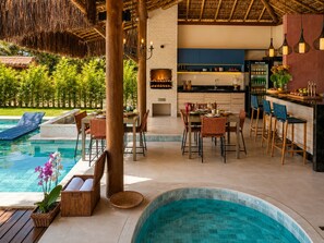Ein Poolbereich mit Bar, Sitzmöglichkeiten und einer Küche.