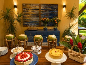 Une table à manger avec une variété de desserts, un buffet bleu et un tableau accroché au mur.