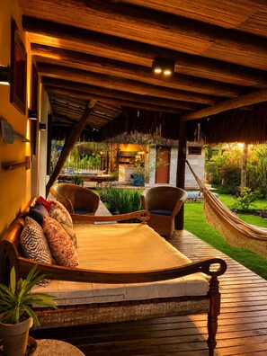 A wooden deck with a hammock, wicker chairs, and a cushioned bench. - Luxury Villa on the Maraú Peninsula | 4 Suites • Heated Pool • Boat & More (Maraú)