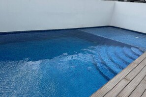 A rectangular swimming pool with a wooden deck edge. - Luxury & Cozy Apartment near Expo GDL / Pool & Gym (Zapopan)