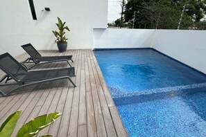 A swimming pool with wooden decking and two lounge chairs. - Luxury & Cozy Apartment near Expo GDL / Pool & Gym (Zapopan)