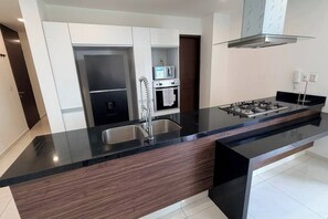 A modern kitchen with a central island, stainless steel appliances, and a sleek black countertop. - Luxury & Cozy Apartment near Expo GDL / Pool & Gym (Zapopan)
