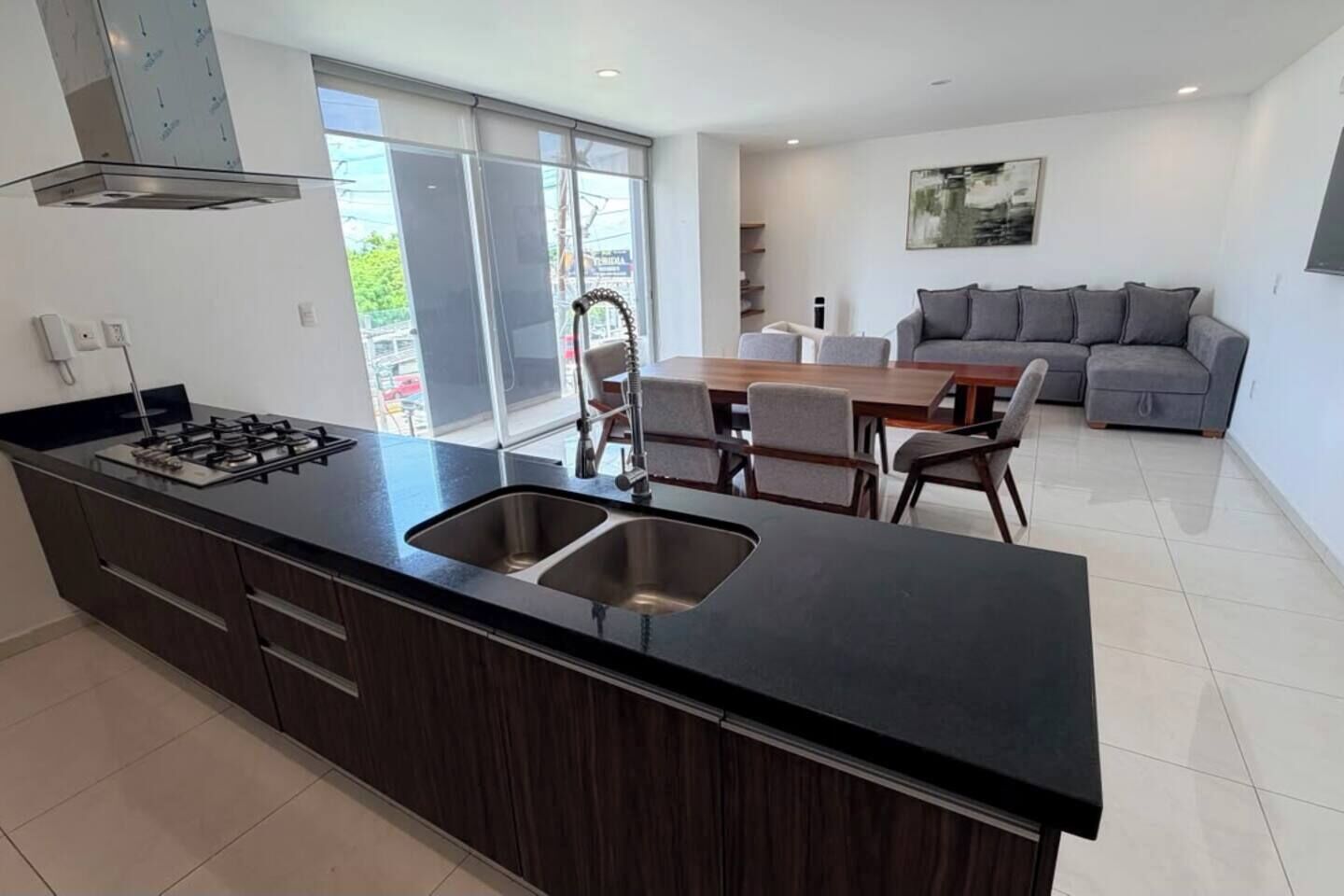 A modern kitchen with a gas stove, double sink, and dining area with chairs and a table.