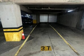 A parking garage with concrete pillars, yellow lines, and a numbered parking space. - Luxury & Cozy Apartment near Expo GDL / Pool & Gym (Zapopan)