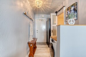 A narrow hallway with a bench, a washing machine, and a door leading to a room. - Oceanview Studio, 2 Pools, Beach, Game Room, Patio (Daytona Beach)