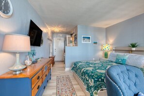 Ein Schlafzimmer mit einem Bett, einem Schminktisch, einem Fernseher, einer Lampe und einem Teppich.