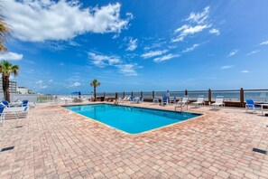 Ein Swimmingpool mit Liegestühlen und Blick aufs Meer.