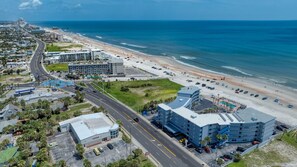 Vue aérienne d’une zone côtière avec un hôtel, une plage et une route.