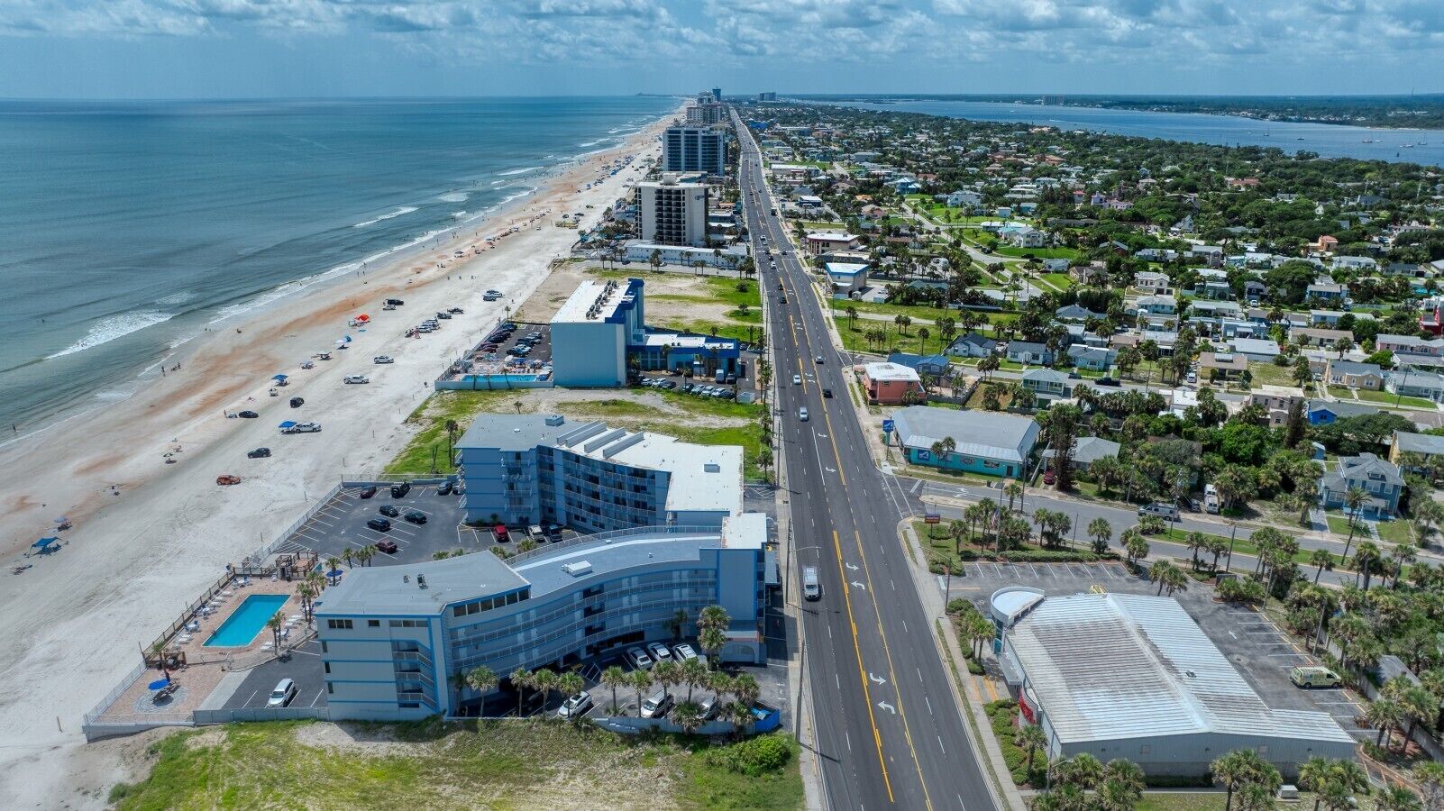 A coastal hotel with a pool, a road, and beachfront.