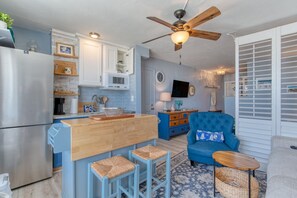 Une cuisine moderne avec un îlot central, un coin repas avec des chaises bleues et un salon avec un canapé bleu.