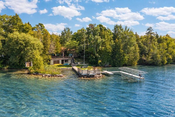 A lakeside property with a dock, a small building, and dense forest.