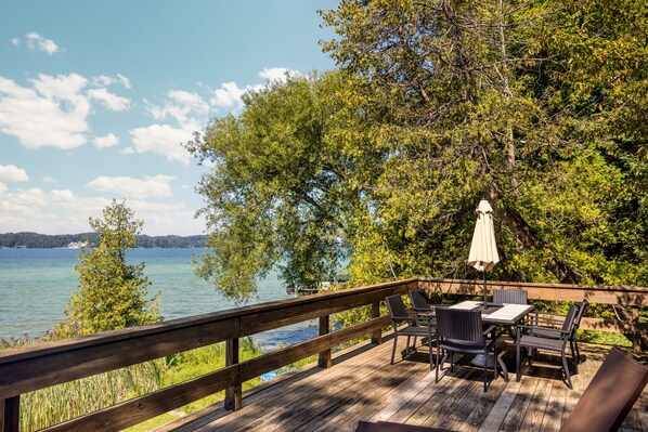 A wooden deck with outdoor furniture and a view of a lake.