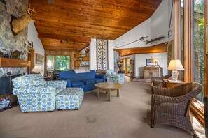 Una sala de estar acogedora con un sofá azul, otomanas estampadas, una mesa de centro de madera y muebles de mimbre.