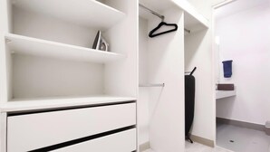 Ein weißer Schrank mit Regalen und Kleiderstange, ein schwarzer Kleiderbügel und ein blaues Handtuch auf einem Ablagegestell.