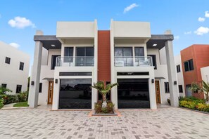 A modern two-story building with large windows, a central entrance, and a paved courtyard. - Coastal Escape in Riviera, Tower Isle - Beach Nearby (St Ann )