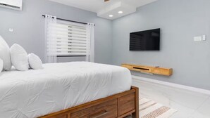 A bedroom with a bed, a TV mounted on the wall, and a ceiling fan. - Coastal Escape in Riviera, Tower Isle - Beach Nearby (St Ann )