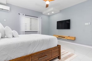 Ein Schlafzimmer mit einem Bett, einem an der Wand befestigten Fernseher und einem Deckenventilator.