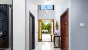 A hallway with a refrigerator, a door, a console table with a mirror, and a light fixture. - Coastal Escape in Riviera, Tower Isle - Beach Nearby (St Ann )