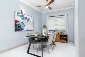 Ein Essbereich mit Tisch, Stühlen, Deckenventilator und Fenster mit Jalousien.