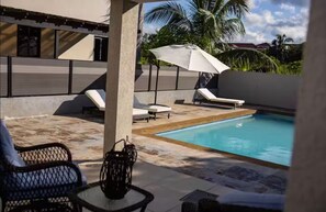 Ein Poolbereich mit Liegestühlen, einem Tisch und einer Zierpflanze.
