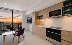 A modern kitchen with a large window, a flat-screen TV, and a view of a sunset. - 4103 - Elevated 1BR with West Views, Pool & 24/7 Gym in Downtown Miami (Miami)