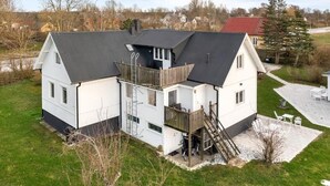 Una casa de dos pisos amb un balcó, una escala i un pati pavimentat.