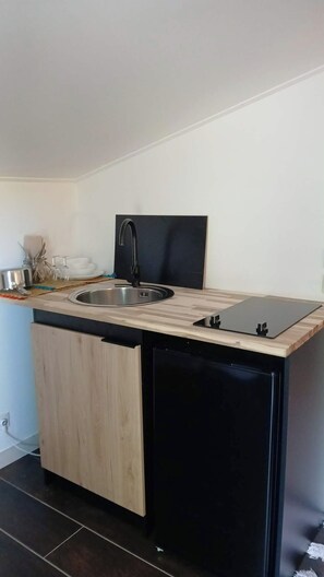 A compact kitchen with a sink, a black countertop, and a black dishwasher.