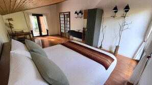 Un dormitorio con una cama grande, suelo de madera, un escritorio y un armario.