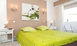 Ein Schlafzimmer mit Bett, Nachttischen, Schreibtisch, Stuhl und Fenster.