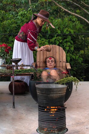 A person in a traditional setting with a wooden chair and a large metal container. - Tree60:· Jungle Villa Private Rooftop&Wood-Hot Tub (Chemuyil)