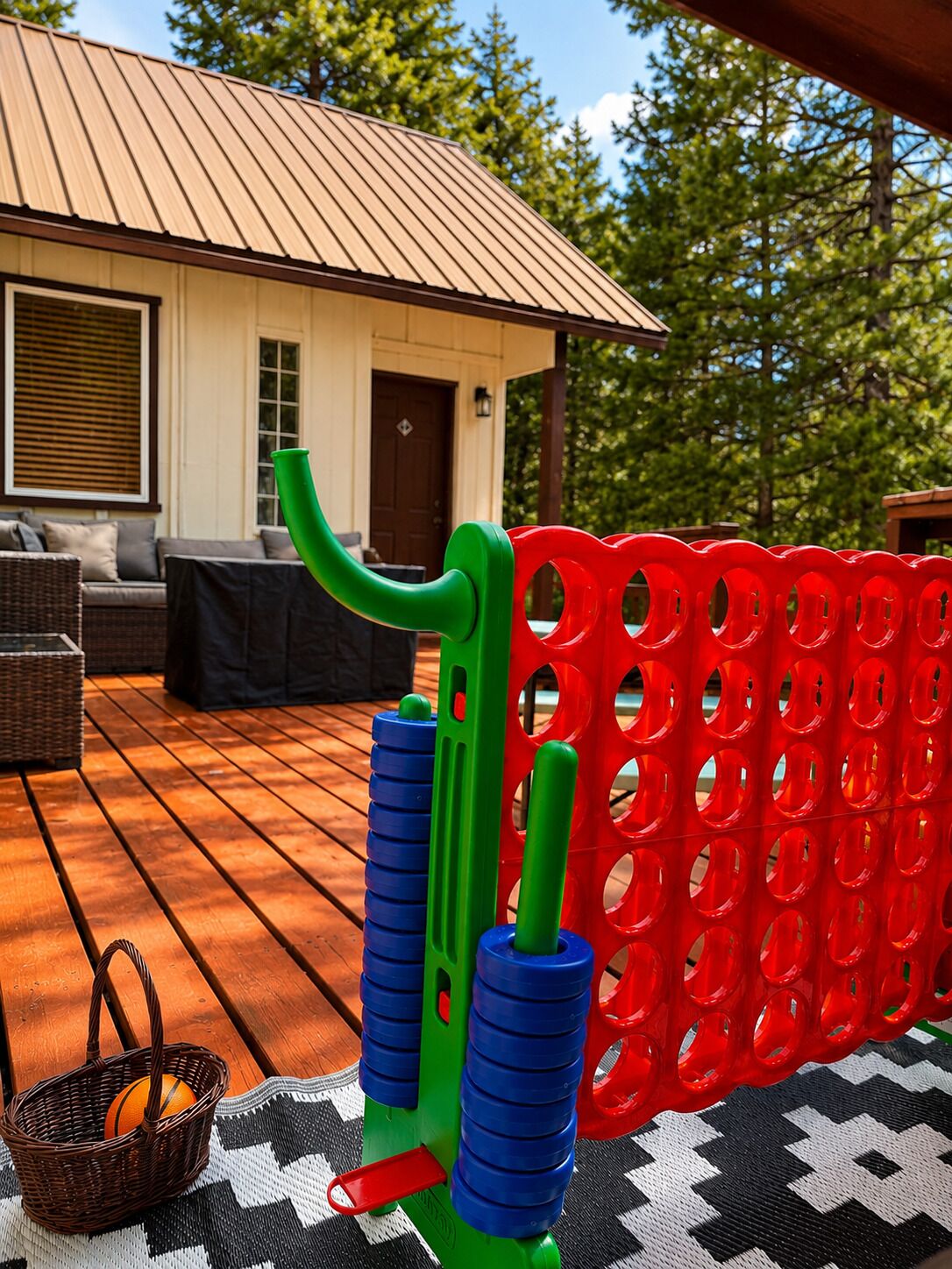 A wooden deck with outdoor furniture, a metal roof, and a red plastic fence.
