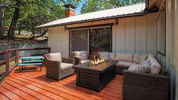 An outdoor deck with wicker furniture, a fire feature, and a covered area with sliding doors.
