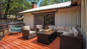 An outdoor deck with wicker furniture, a fire feature, and a covered area with sliding doors.