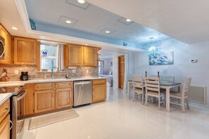 A modern kitchen with wooden cabinets, a built-in dishwasher, and a dining area with a table and chairs. - Pet-Friendly Daytona Beach Home Near the Beach (Daytona Beach)