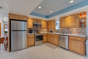 A modern kitchen with stainless steel appliances, wooden cabinets, and a tiled floor. - Pet-Friendly Daytona Beach Home Near the Beach (Daytona Beach)