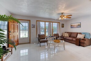 A spacious living room with a brown leather sofa, two armchairs, a coffee table, and a ceiling fan. - Pet-Friendly Daytona Beach Home Near the Beach (Daytona Beach)