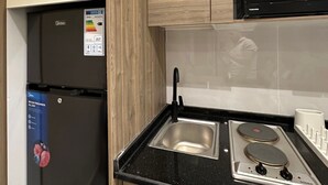 A kitchen with a black refrigerator, a stainless steel sink, and a black stove. - 302 Al-najeh JRE Apartments For Rent ave (Amman)