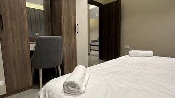 A hotel room with a bed, a desk, and a chair.