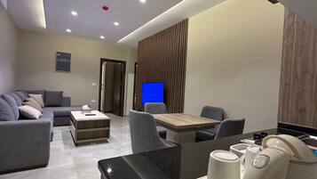 A modern living room with a sofa, a coffee table, and a dining area with chairs and a table.