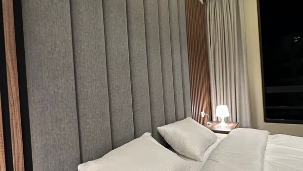 A modern hotel room with a large bed, a nightstand, and a window with curtains. - 302 Al-najeh JRE Apartments For Rent ave (Amman)