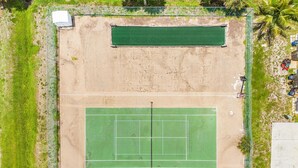 An aerial view of a tennis court surrounded by a fence, with a small building and parked vehicles nearby. - Adorable 2 Bedroom Condo - Pool & Prime Location (Fort Myers)