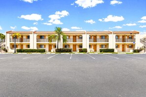A multi-story motel with a parking lot in front. - Adorable 2 Bedroom Condo - Pool & Prime Location (Fort Myers)